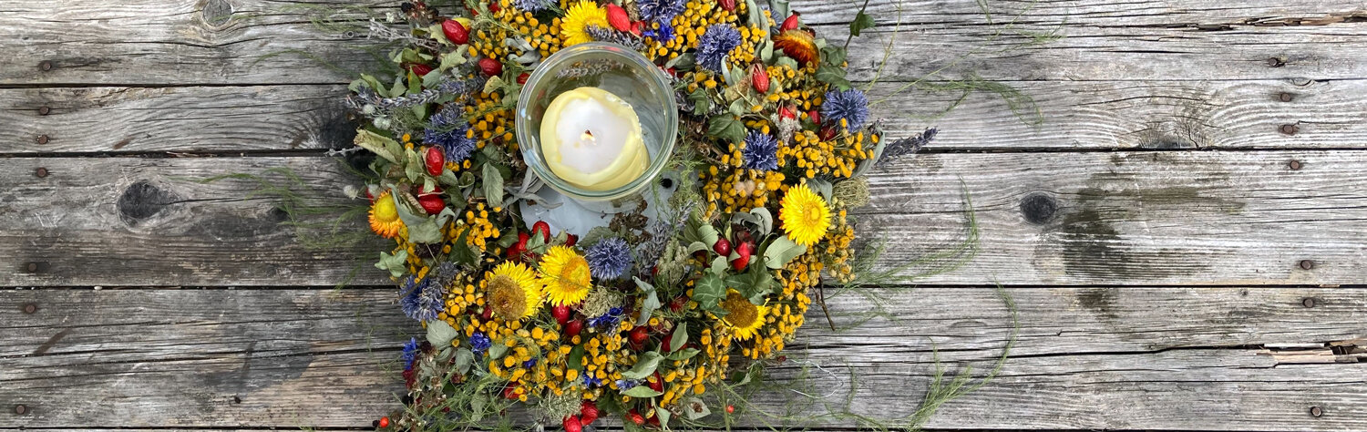 Homemade colourful autumn wreath of flowers and berries with a candle holder on a wooden table