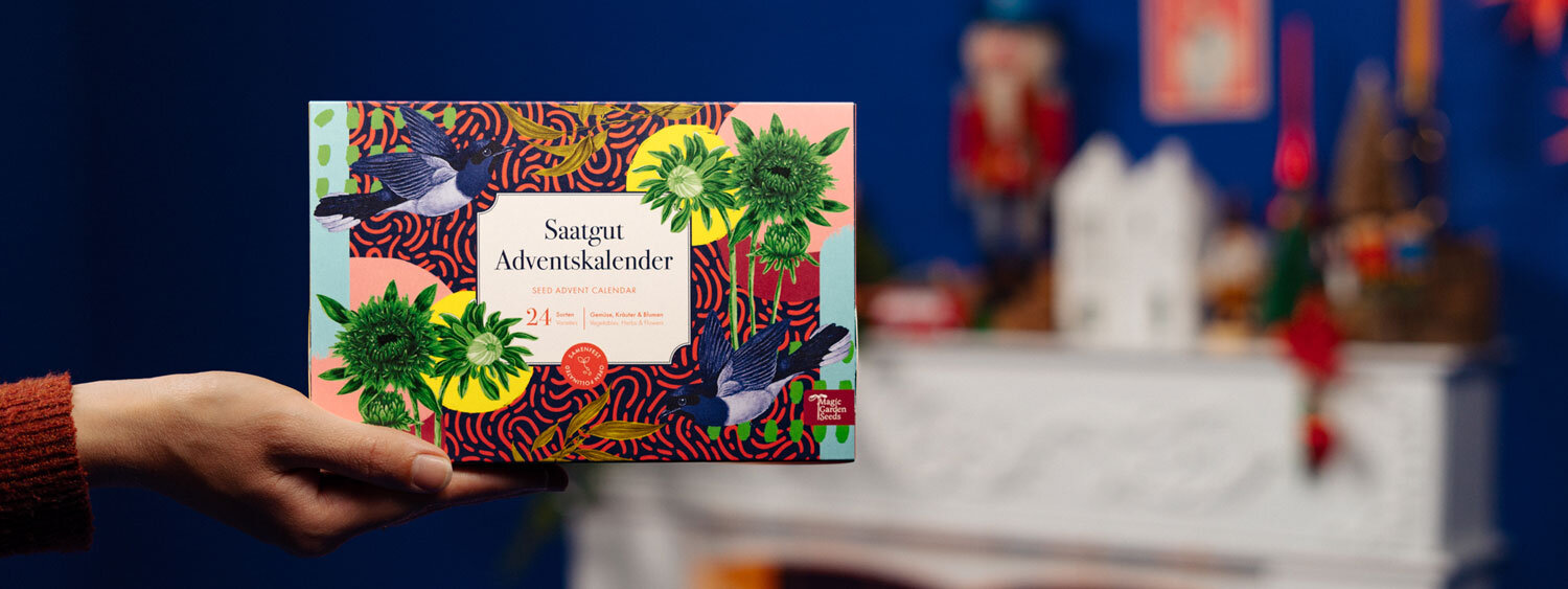 Seed advent calendar “Vegetables, Herbs & Flowers” held in front of a festively decorated fireplace