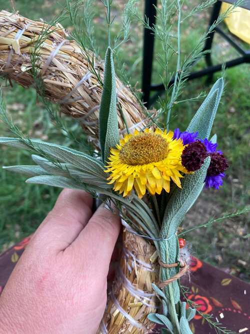 Wreath making: a small bunch of flowers and leaves is tied onto a straw wreath base