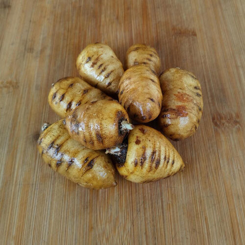 Harvested turnip-rooted chervil roots on a wooden board